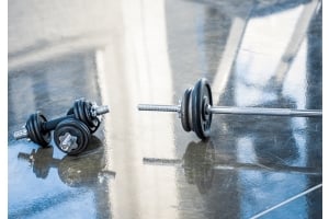 Hantlar och skivstång på ett blankt golv i ett gym