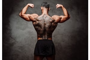 Närbild på en bred, vältränad rygg med tatueringar