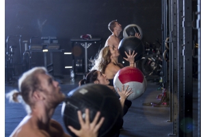 En crossfitgrupp använder gymbollar mot en vägg