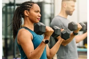 En kvinna och en man tränar med gummerade hexhantlar på ett gym