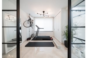 Hemmagym med löpband, glasdörrar och en cykel hängandes på väggen