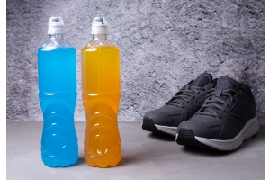 En blå och en orange vattenflaska framför ett par svarta sneakers