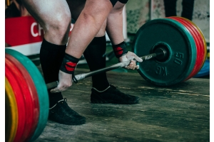 En man med wrist wraps förbereder sig för att lyfta en tung skivstång