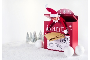 En tomtenisse stoppar in brev i en röd brevlåda till tomten