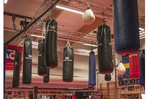 Många svarta nordic fighter boxningssäckar som hänger i ett tak på en boxningsklubb
