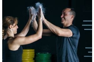 Ett par gör high five i gymmet med chalk på händerna