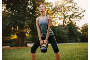 En start kvinna gör kettlebell swings utomhus