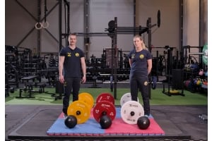 En man och en kvinna från styrkelyftförbundet visar upp Thor fitness viktstänger och viktskivor