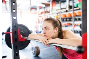 En ung kvinna funderar i ett gym